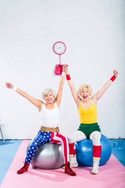 Fitness topları üzerinde oturan ve kameraya gülümseyen heyecan üst düzey sportswomen 