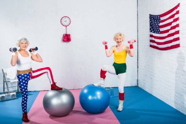dambıl ile egzersiz ve spor salonunda kamera gülümseyen sportif üst düzey kadın