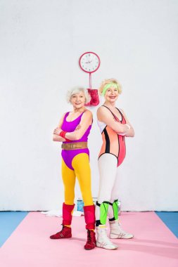 çapraz kolları ile ayakta ve kameraya gülümseyen mutlu üst düzey sportswomen
