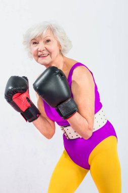 Boks eldivenleri gri izole kamera gülümseyen güzel sportif üst düzey Bayan portresi