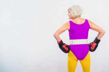 Arkadan boks eldiven eller gri izole bel ile ayakta sportif kadın kıdemli görünüşü