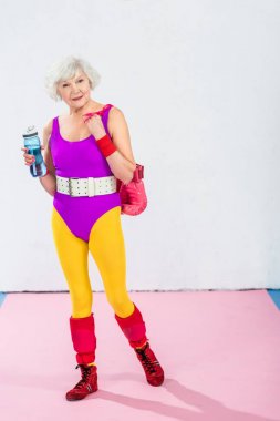 şişe su ve boks eldivenleri kameraya gülümseyen ile sportif üst düzey Bayan tam boy görmek