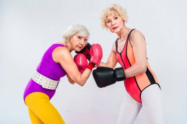 üst düzey sportswomen boks eğitimi ve gri izole kamera bakarak eldiven yan görünüm