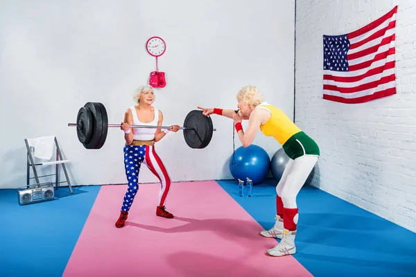 Sportliche Seniorin Bläst Trillerpfeife Und Schaut Ältere Sportlerin Beim Hantelheben — Stockfoto