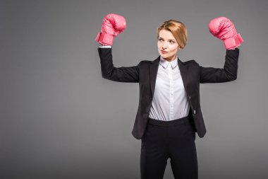 strong businesswoman posing in boxing gloves, isolated on grey