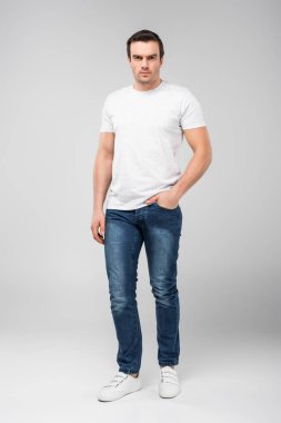 yakışıklı adam gri izole kamera, bakarak cebinde el ile 