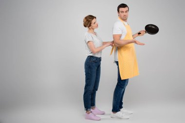 wife and husband in apron with frying pan, feminism concept, isolated on grey clipart