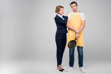 businesswoman and male upset householder with frying pan hugging together, feminism concept, isolated on grey clipart