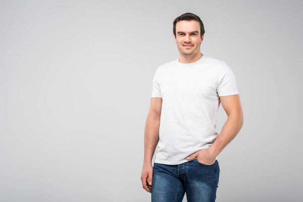 smiling handsome man with hand in pocket, isolated on grey