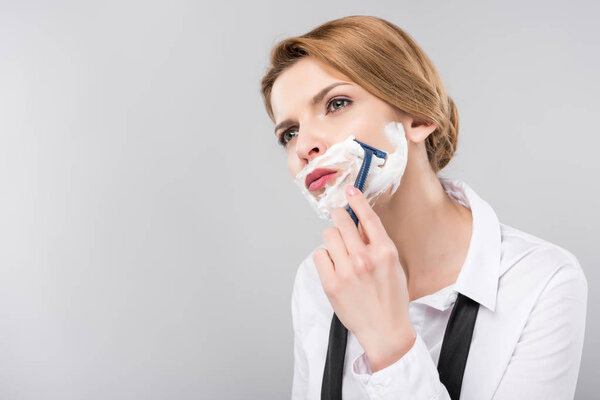 beautiful businesswoman shaving face her face, isolated on grey, feminism concept
