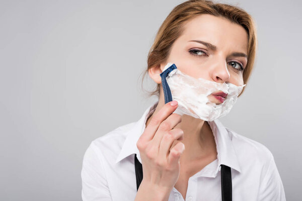 businesswoman shaving face her face, isolated on grey, feminism concept