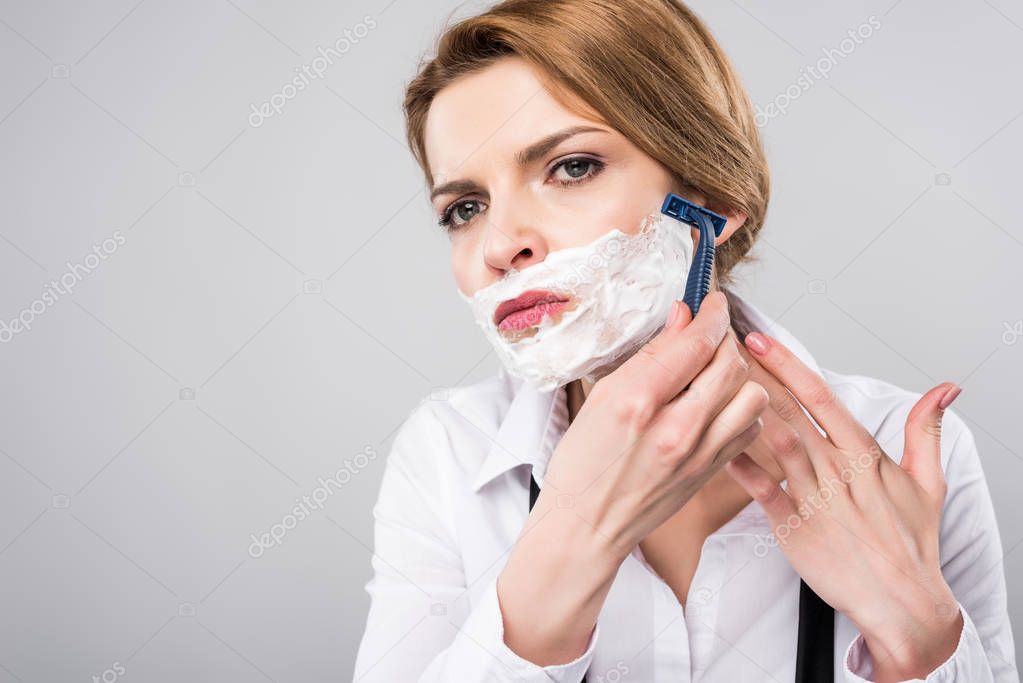 Businesswoman in shaving foam with razor, isolated on grey, feminism concept