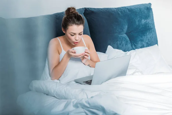 Frau arbeitet mit Laptop im Bett — Stockfoto