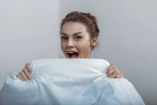 Woman covering face with bedcover — Stock Photo