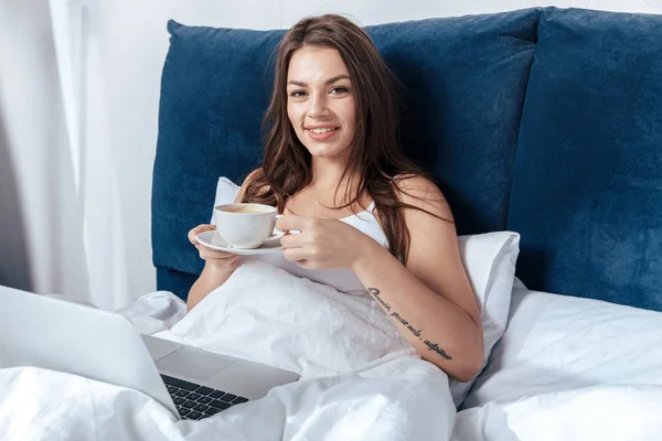Woman working on laptop in bed — Stock Photo