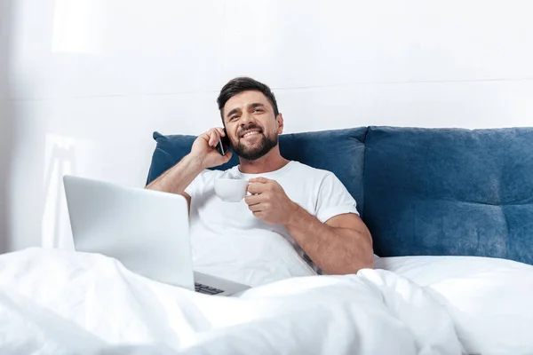 Young man talking on phone in bed — Stock Photo