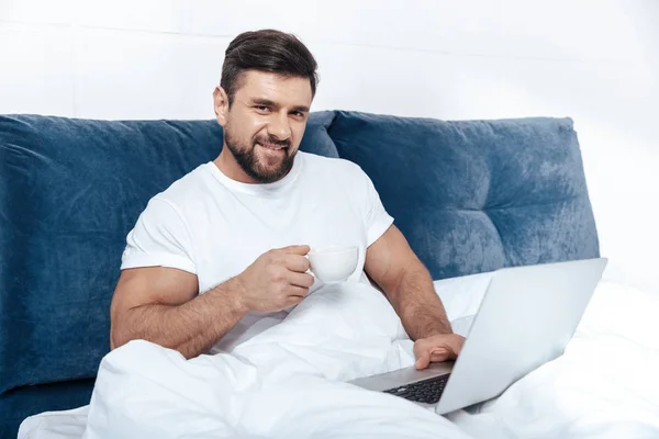 Mann arbeitet am Laptop im Bett — Stockfoto