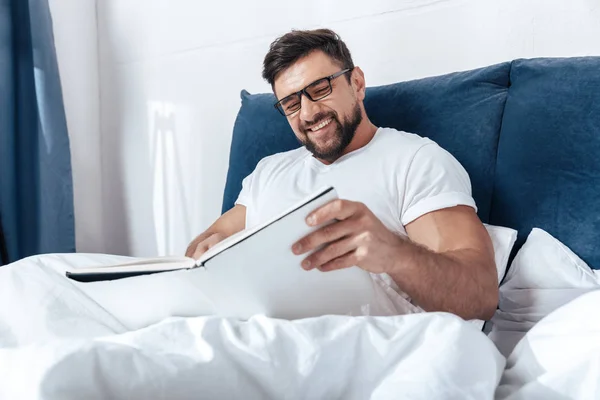 Hombre leyendo revista en la cama - foto de stock