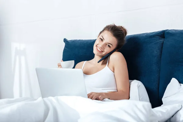 Mujer trabajando en el ordenador portátil en la cama - foto de stock