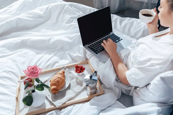 Mujer joven usando portátil en la cama - foto de stock