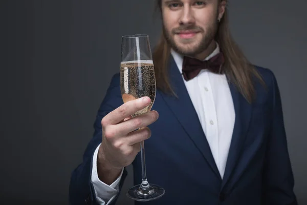 Man in tuxedo holding glass with champagne — Stock Photo