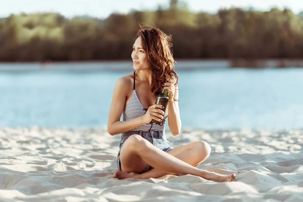 Woman drinking beer on beach — Stock Photo