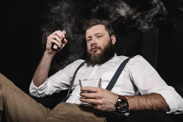 Uomo elegante vaping con bicchiere di whisky — Foto stock