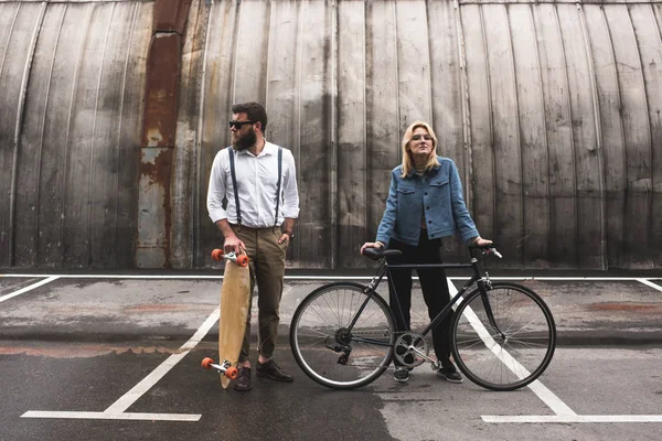 Stylish couple with bicycle and longboard — Stock Photo