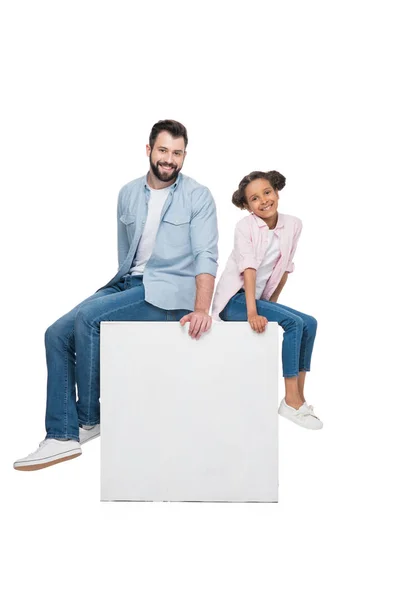 Father and daughter sitting on cube — Stock Photo