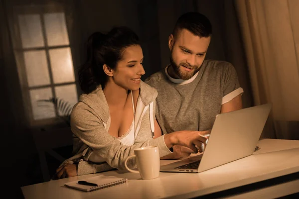 Giovane coppia utilizzando il computer portatile a casa — Foto stock