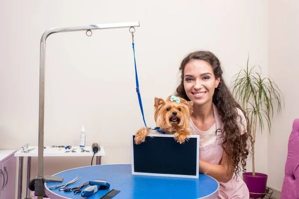 Groomer e cão com placa em branco — Fotografia de Stock