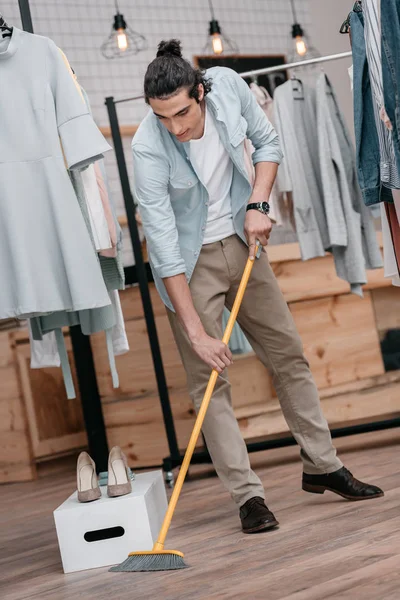 Man sweeping floor in boutique — Stock Photo