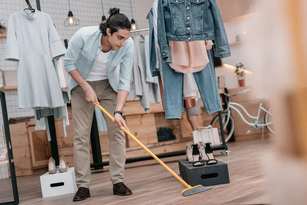 Man sweeping floor in boutique — Stock Photo