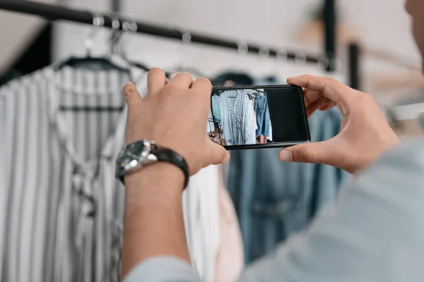 Hombre fotografiando ropa con smartphone - foto de stock