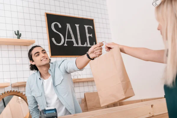 Seller giving shopping bag to client — Stock Photo