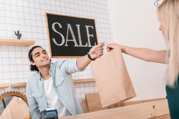 Vendedor dando saco de compras ao cliente — Fotografia de Stock