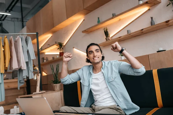 Triumphing young man in boutique — Stock Photo