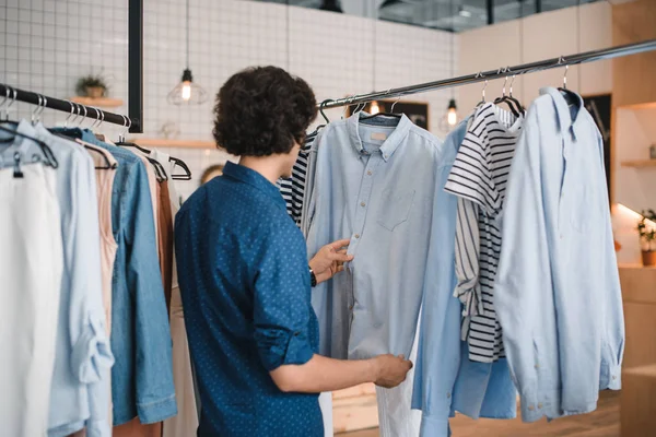Homme choisissant chemises en boutique — Photo de stock