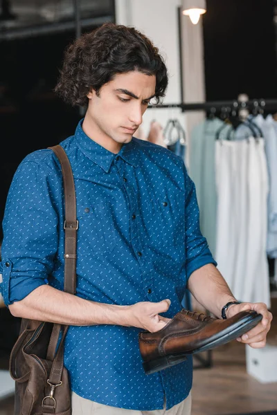 Uomo in possesso di scarpe in boutique — Foto stock