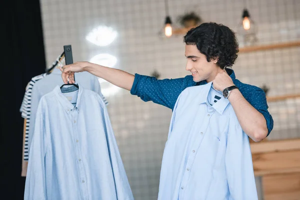 Мужчина выбирает рубашки в бутике — стоковое фото