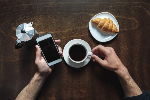 Using smartphone and drinking coffee — Stock Photo