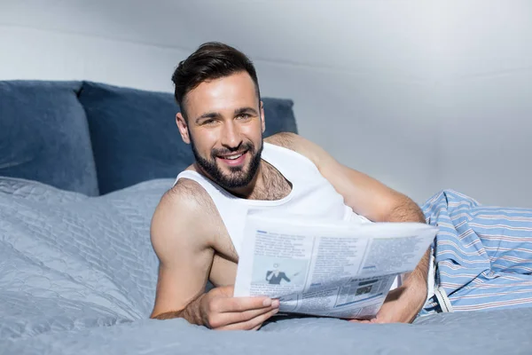 Bearded man reading newspaper in bed — Stock Photo