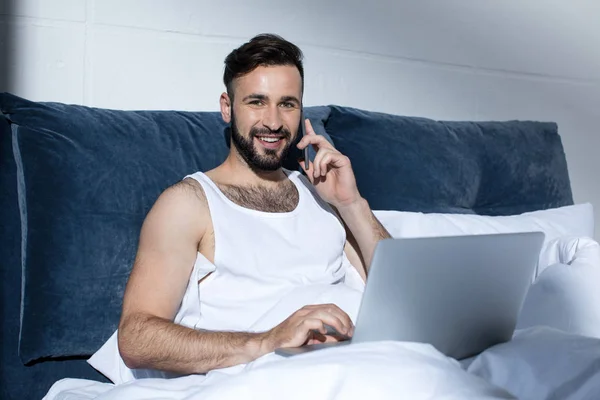 Homem barbudo usando gadgets na cama — Fotografia de Stock