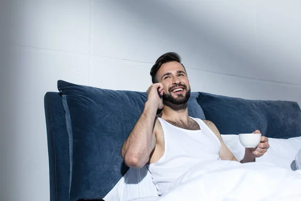 Schöner Mann mit Smartphone im Bett — Stockfoto