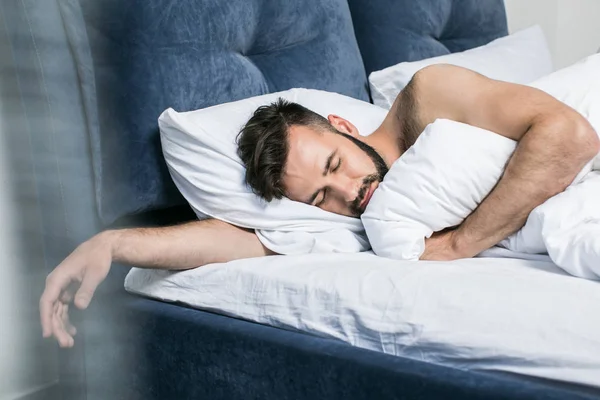 Schöner junger Mann schläft im Bett — Stockfoto