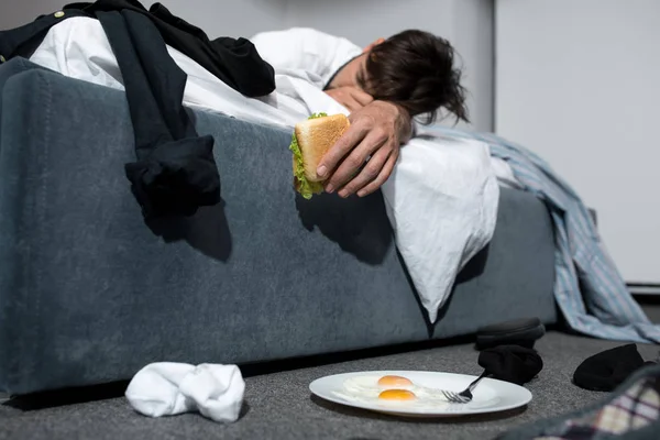 Young man sleeping on bed with food — Stock Photo