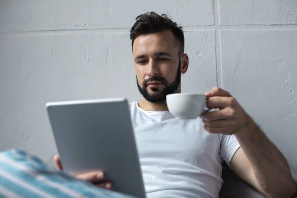 Hombre leyendo la tableta y beber café - foto de stock