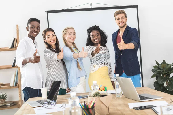 Empresarios multiétnicos mostrando pulgares hacia arriba - foto de stock