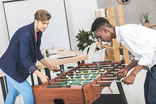 Hombres de negocios multiculturales jugando futbolín - foto de stock