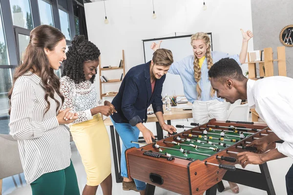 Multicultural colleagues playing table football — Stock Photo